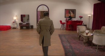 Movie still from “Opening Night” (1977), directed by John Cassavetes – A man wearing a long coat walking in front of a mirror; Wide shot, Over the shoulder angle