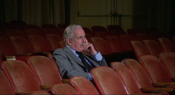 Movie still from “Opening Night” (1977), directed by John Cassavetes – An older man sitting in an empty theater; Medium shot, High angle