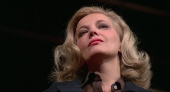 A woman with blonde curly hair looking up at the sky