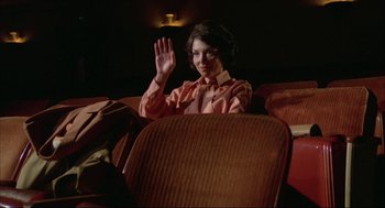 Movie still from “Opening Night” (1977), directed by John Cassavetes – A woman sitting in a chair waving at the camera; Medium shot, Low angle