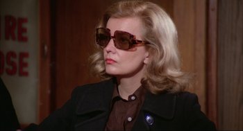 Movie still from “Opening Night” (1977), directed by John Cassavetes – A woman with blonde hair wearing sunglasses and a brown shirt; Close Up shot, Over the shoulder angle