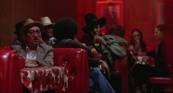 Movie still from “Opening Night” (1977), directed by John Cassavetes – A group of people sitting in a red room; Medium shot, Over the shoulder angle