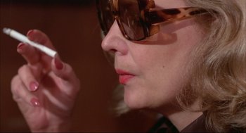 Movie still from “Opening Night” (1977), directed by John Cassavetes – A person wearing sunglasses and holding a cigarette; Extreme Close Up shot, Over the shoulder angle