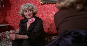 Movie still from “Opening Night” (1977), directed by John Cassavetes – An older woman sitting on a chair with a rose in her mouth; Close Up shot, Over the shoulder angle