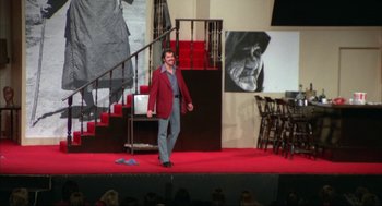 Movie still from “Opening Night” (1977), directed by John Cassavetes – A man wearing a red jacket on a red carpet; Wide shot, Low angle