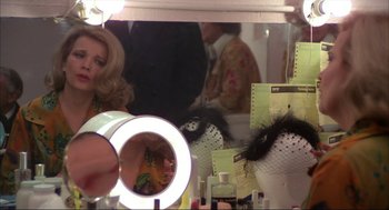 Movie still from “Opening Night” (1977), directed by John Cassavetes – A woman looking in the mirror in front of a mirror; Medium shot, Over the shoulder angle
