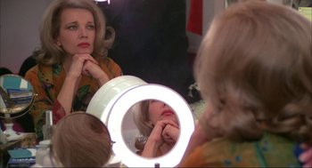 Movie still from “Opening Night” (1977), directed by John Cassavetes – A woman looking in a mirror while holding her hand to her face; Close Up shot, High angle