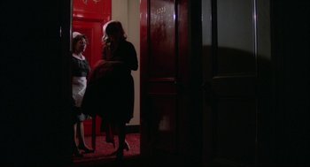 Movie still from “Opening Night” (1977), directed by John Cassavetes – Two women standing next to each other in front of a red door; Wide shot, High angle