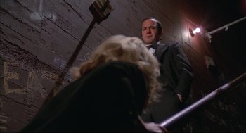Movie still from “Opening Night” (1977), directed by John Cassavetes – A man standing next to another man in a suit; Medium shot, Low angle