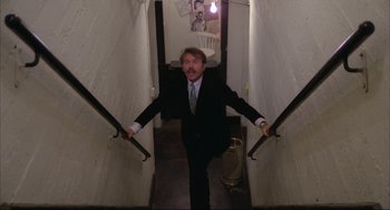 Movie still from “Opening Night” (1977), directed by John Cassavetes – A man wearing a suit and tie walking down a flight of stairs; Wide shot, High angle