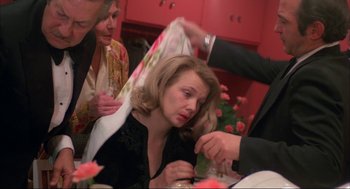 Movie still from “Opening Night” (1977), directed by John Cassavetes – A woman sitting at a dinner table with a napkin over her face; Medium shot, Over the shoulder angle