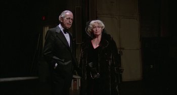 Movie still from “Opening Night” (1977), directed by John Cassavetes – An older man standing next to an older woman; Medium shot, Low angle