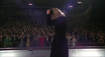 Movie still from “Opening Night” (1977), directed by John Cassavetes – A woman standing in front of an audience holding her hand to her face; Wide shot, Over the shoulder angle