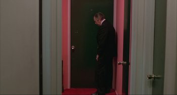Movie still from “Opening Night” (1977), directed by John Cassavetes – A man standing in front of a green door; Wide shot, High angle