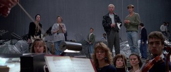 Movie still from “Opera” (1987), directed by Dario Argento – A group of people standing in front of a sheet music; Wide shot, Low angle