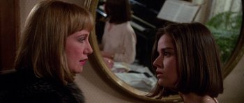 Movie still from “Opera” (1987), directed by Dario Argento – A woman looking at her reflection in a mirror; Close Up shot, Over the shoulder angle