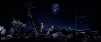Movie still from “Opera” (1987), directed by Dario Argento – A woman standing in a pile of rubble at night; Extreme Wide shot, Low angle