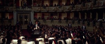 Movie still from “Opera” (1987), directed by Dario Argento – A large group of people sitting in a room; Wide shot, Low angle