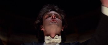 Movie still from “Opera” (1987), directed by Dario Argento – A man in a suit and bow tie looking up; Close Up shot, Low angle