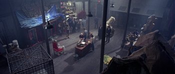 Movie still from “Opera” (1987), directed by Dario Argento – A group of people standing around a room; Extreme Wide shot, High angle