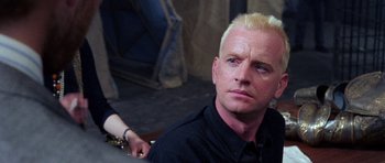 Movie still from “Opera” (1987), directed by Dario Argento – A man with blonde hair and a black shirt; Close Up shot, Over the shoulder angle