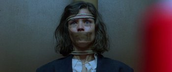 Movie still from “Opera” (1987), directed by Dario Argento – A woman with taped up mouth standing next to a wall; Close Up shot, Low angle