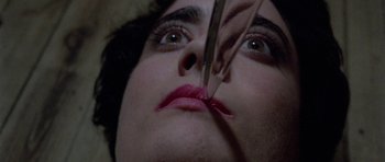Movie still from “Opera” (1987), directed by Dario Argento – A woman is holding a pair of tweezers in her mouth; Extreme Close Up shot, Overhead angle