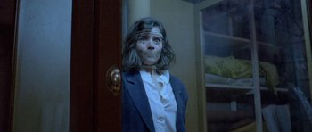 Movie still from “Opera” (1987), directed by Dario Argento – A woman with a face paint standing in front of a door; Close Up shot, Low angle