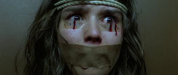 Movie still from “Opera” (1987), directed by Dario Argento – A woman with taped mouth and blood on her face; Extreme Close Up shot, Overhead angle