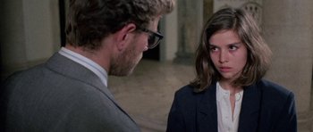 Movie still from “Opera” (1987), directed by Dario Argento – A man and a woman in a suit and tie talking to each other; Close Up shot, Over the shoulder angle