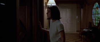 Movie still from “Opera” (1987), directed by Dario Argento – A young woman standing next to a door; Medium shot, Over the shoulder angle