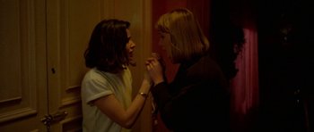 Movie still from “Opera” (1987), directed by Dario Argento – Two women are holding hands in a room; Close Up shot, High angle