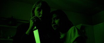 Movie still from “Opera” (1987), directed by Dario Argento – Two women in a dark room with a green light in the background; Close Up shot, Low angle