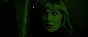 Movie still from “Opera” (1987), directed by Dario Argento – A woman looking out a window at night with green lights; Close Up shot, Low angle