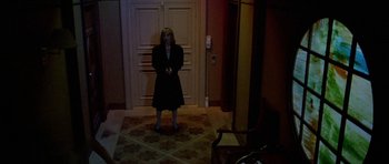 Movie still from “Opera” (1987), directed by Dario Argento – A woman standing in front of an open door; Wide shot, High angle