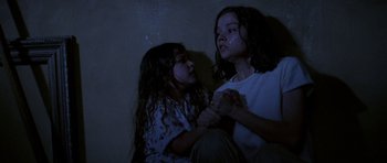 Movie still from “Opera” (1987), directed by Dario Argento – Two young girls sitting on the ground in a dark room; Medium shot, High angle