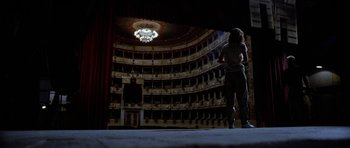 Movie still from “Opera” (1987), directed by Dario Argento – A person standing in a room that has a lot of lights in it; Extreme Wide shot, Low angle