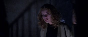 Movie still from “Opera” (1987), directed by Dario Argento – A woman with long blonde curly hair looking at the camera; Close Up shot, Low angle