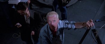 Movie still from “Opera” (1987), directed by Dario Argento – A man with blonde hair is standing in the dark; Medium shot, Low angle
