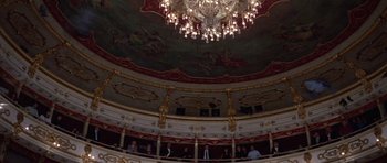 Movie still from “Opera” (1987), directed by Dario Argento – People are sitting in a theater with a chandelier above them; Extreme Wide shot, Overhead angle