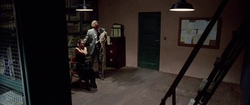 Movie still from “Opera” (1987), directed by Dario Argento – A man and a woman standing in front of a door; Wide shot, High angle
