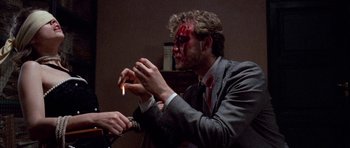 Movie still from “Opera” (1987), directed by Dario Argento – A man in a business suit with blood all over his face; Medium shot, Over the shoulder angle