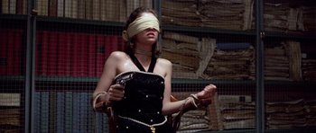 Movie still from “Opera” (1987), directed by Dario Argento – A blindfolded woman holding a cell phone in her hands; Medium shot, High angle