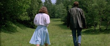 Movie still from “Opera” (1987), directed by Dario Argento – A man and a woman are walking through a field; Wide shot, High angle