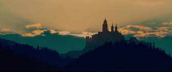 A castle on top of a hill with a sunset in the background