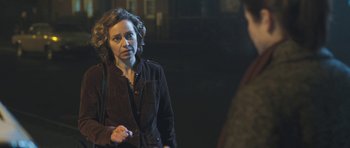 Movie still from “Oranges and Sunshine” (2010), directed by Jim Loach – A woman standing next to a man in a dark room; Close Up shot, Over the shoulder angle