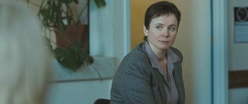 Movie still from “Oranges and Sunshine” (2010), directed by Jim Loach – A woman sitting in a chair in front of a plant; Close Up shot, Over the shoulder angle