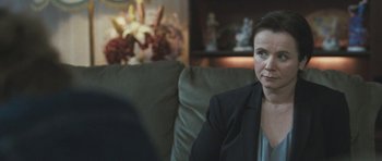 Movie still from “Oranges and Sunshine” (2010), directed by Jim Loach – A woman sitting on top of a couch in a room; Close Up shot, Over the shoulder angle