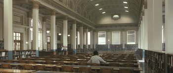 Movie still from “Oranges and Sunshine” (2010), directed by Jim Loach – A man sitting in a library with a bunch of books; Extreme Wide shot, High angle