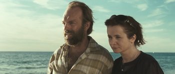 Movie still from “Oranges and Sunshine” (2010), directed by Jim Loach – A man and a woman standing next to each other on the beach; Close Up shot, Low angle